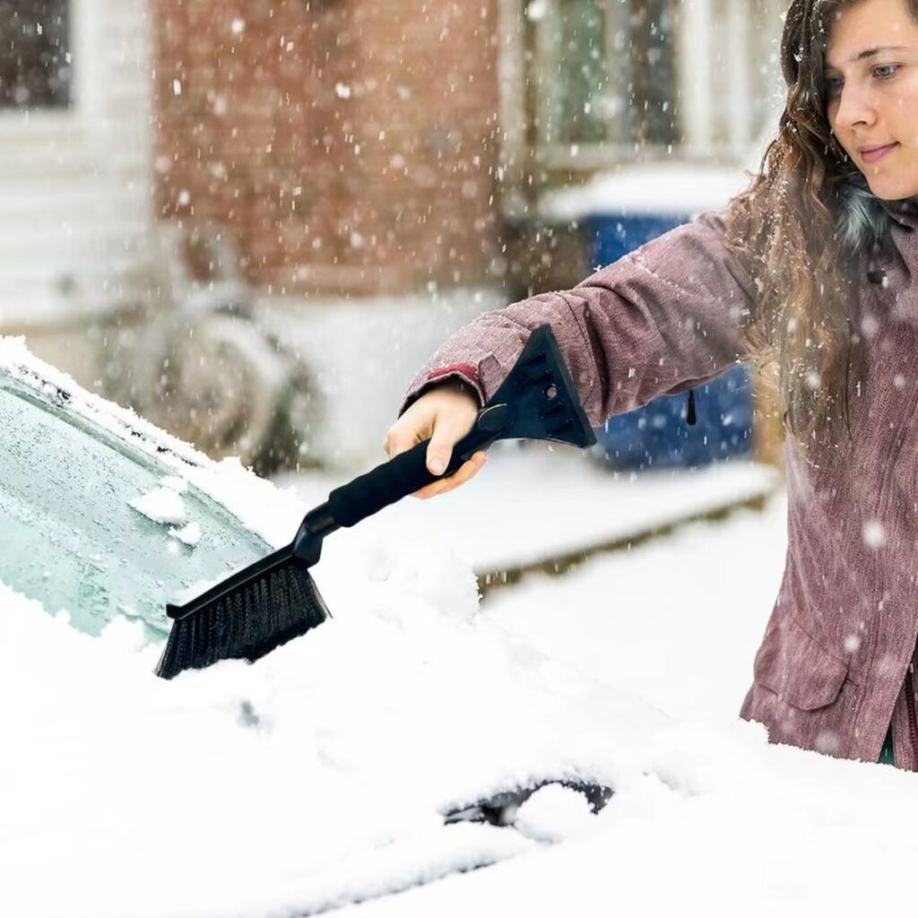 Person brushing snow off a windshield